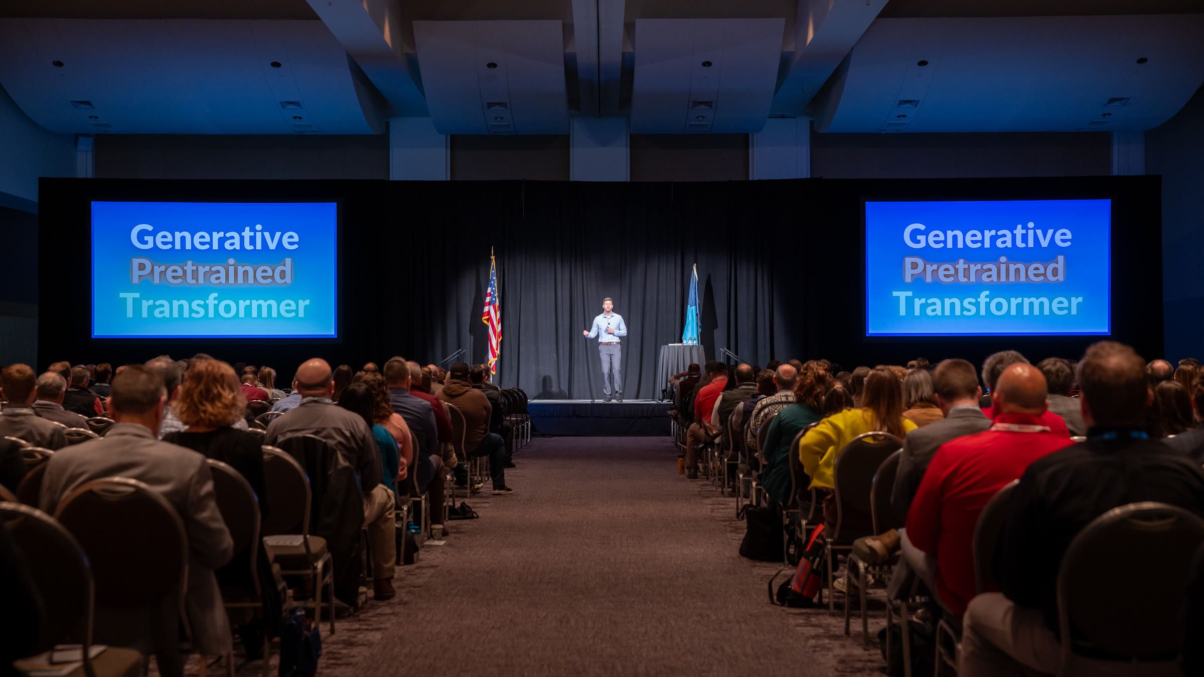 A packed ballroom during a keynote, seen from the back of the room.
