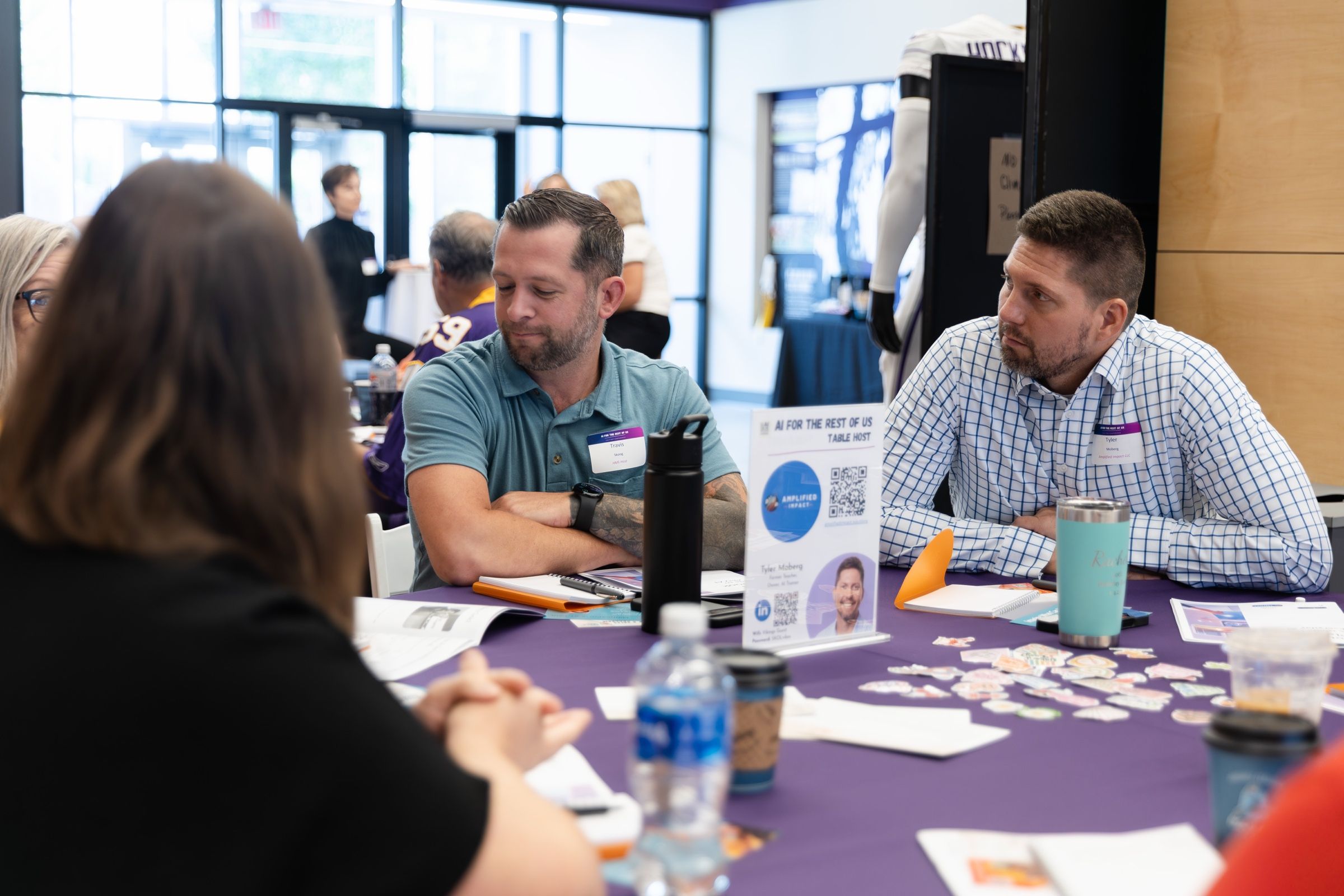 Two participants talking through an idea at a workshop table covered in materials.